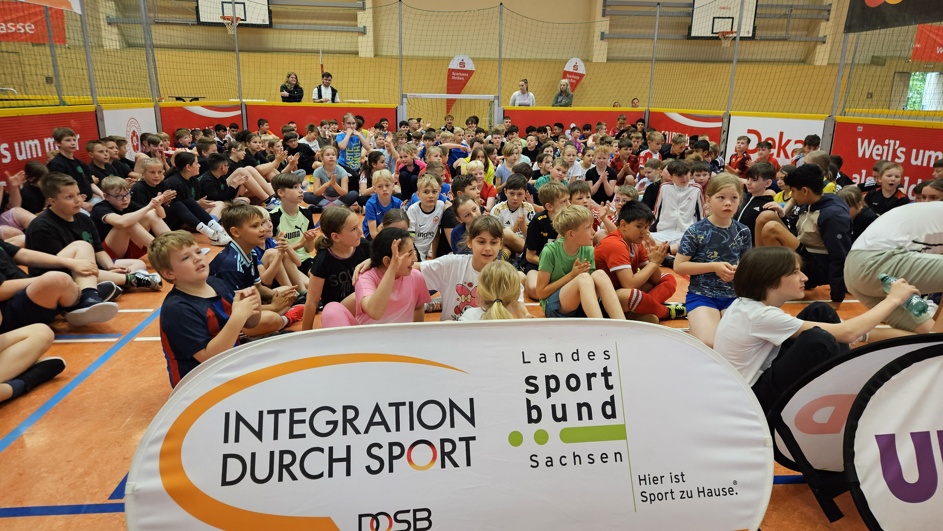 Teilnehmende sitzende im Spielfeld hinter dem Logo des Landessportbundes