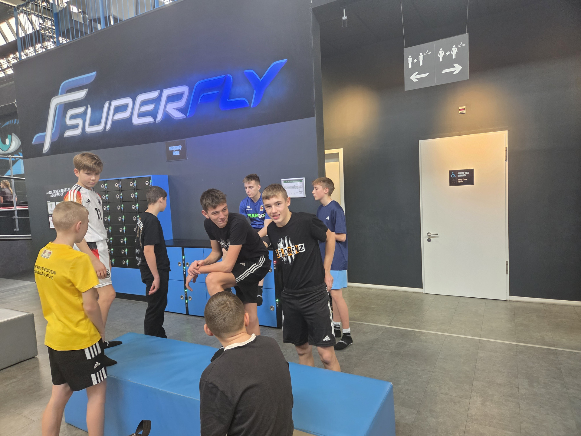 Schüler am Eingang zur Trampolinhalle mit Logo Superfly im Hintergrund