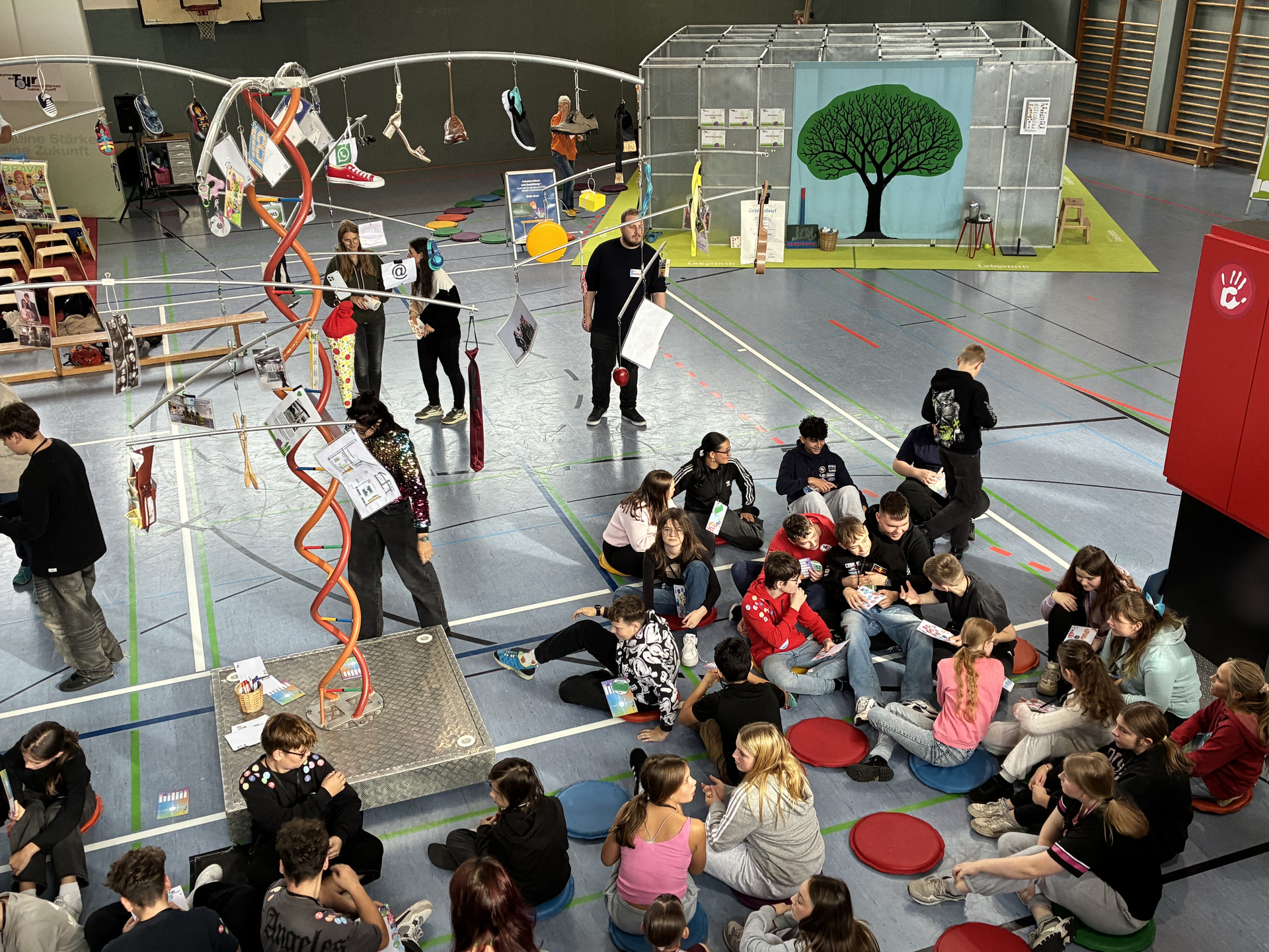 Teilnehmende Schüler sitzen entspannt auf dem Boden der Veranstaltungshalle