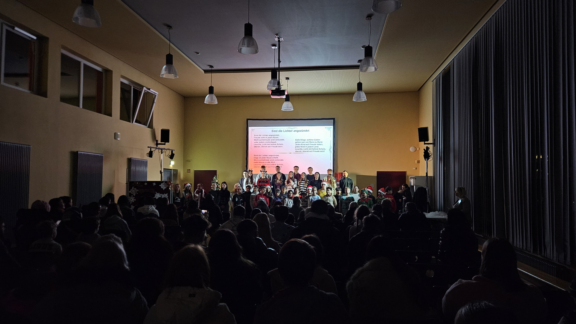 Zuschauer verfolgen das Singen der Schüler auf der Bühne